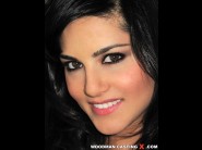 Sunny leone is sited on a sofa, legs appart and looking at you