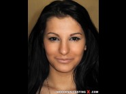 Bagyraa is sited on a sofa, legs appart and looking at you