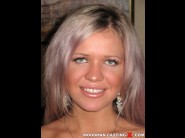 Cristal may is sited on a sofa, legs appart and looking at you