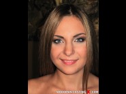 Amy sky is sited on a sofa, legs appart and looking at you