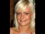 Corinne is sited on a sofa, legs appart and looking at you