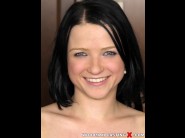 Mounia is sited on a sofa, legs appart and looking at you