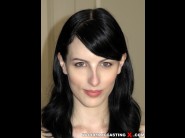 Alex harper is sited on a sofa, legs appart and looking at you